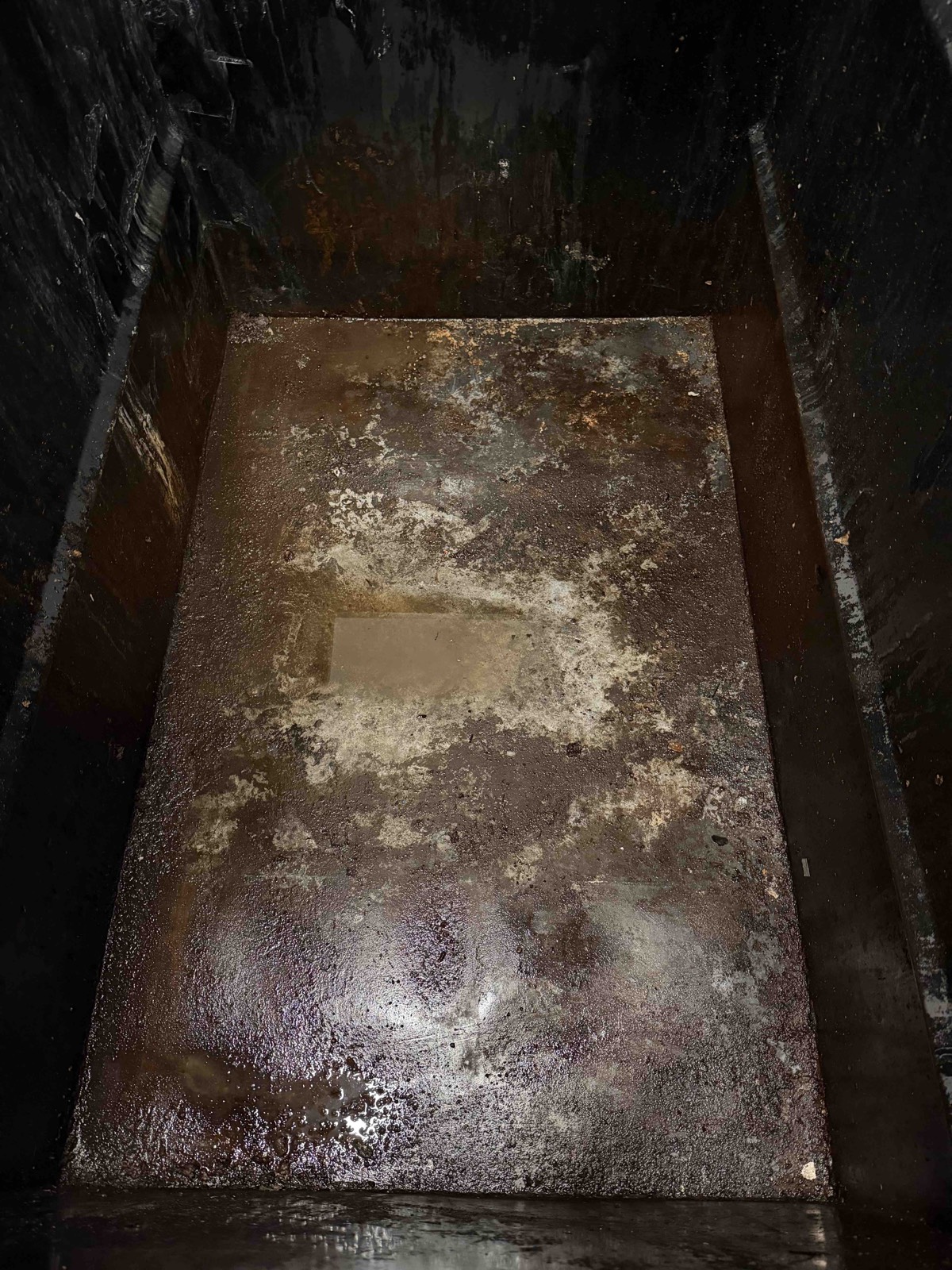 Grease-stained dumpster interior floor before professional degreasing in Ventura County