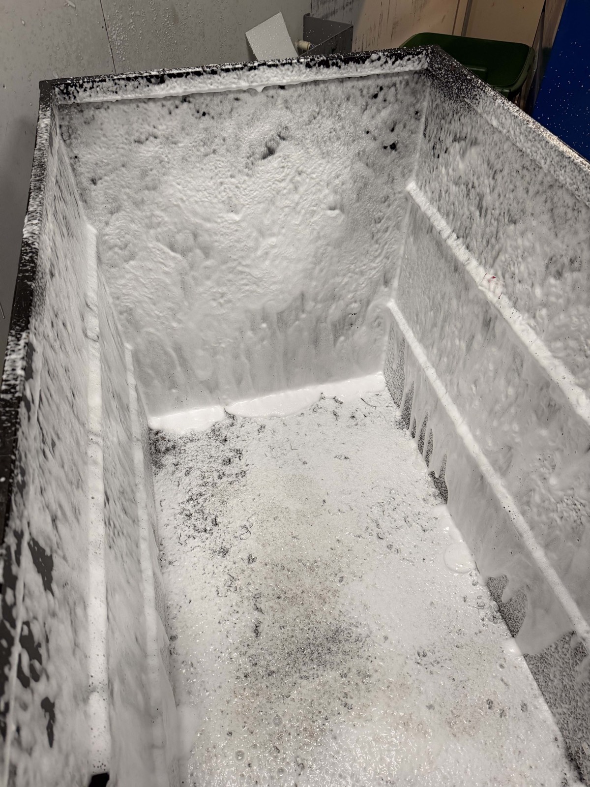Dumpster interior being degreased with cleaning solution during professional pad cleaning service